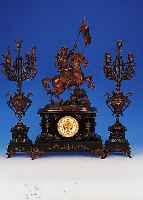 Groáe Kaminuhr, mit zwei groáen Kerzenbeistel-lern, Frankreich, um 1900, schwarzer Schie- fersockel mit Ornamenten, Messingfáe patin., seitl. ...