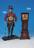 TISCHUHR IN FORM EINER STANDUHR, WOHL ENGLAND,UM 1930/40, VERZIERTES HOLZGEHäUSE, GLASAB- DECKUNG, METALLZIFFERBLATT, STIFTENANKERGANG- WERK, ...
