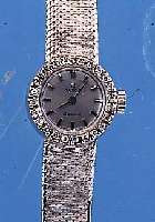 OMEGA DAMENGOLDBANDUHR, SCHWEIZ UM 1964, NEUTR. WG 750/000-GEH. INCL. WG-FLECHTBAND RODH., LüNETTE AUFWEND. M. 24 8/8 DIAMANTEN ZUS. CA. ...