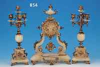 KAMINUHR MIT ZWEI BEISTELLERN, FRANKREICH, UM 1900, VERZIERTES ALABASTERGEHäUSE MIT MES- SINGGUßAPPLIKATIONEN BESETZT, DREI BEMALTE KARTUSCHEN ...