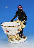 TAFELAUFSATZ, MEISSEN, 18. JH., AFRIKA, DARST. EINES FARBIGEN MIT SCHALE, WANDUNG IN TEILREL. KORBGEFLECHT, BUNTE BLUMENMALEREI, DREI ...