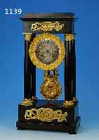 FRüHE PORTALUHR, FRANKREICH, UM 1840/50, SCHWARZ GELACKTES HOLZGEHäUSE, IN STRENGER SYMETRIE, KAPITELLE-BASEN- UND PHLINTEN VER- GOLDET, ...