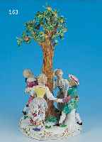 PORZELLANFIGUR, MEISSEN, UM 1780, VIER KIN- DER TANZEN EINEN REIGEN UM APFELBAUM, BUNTE BEMALUNG, GOLDSTAFFAGE, REICH APPLIZIERTE BLäTTER, AN ...