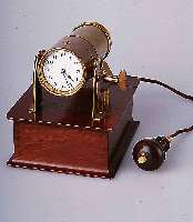 NACHTTISCHUHR, WOHL ENGLAND UM 1908 M. EIGE-NER LICHTQUELLE (4.5 VOLT BATTERIE), IM HOLZKASTEN, MESSINGGEH., LINSE ZUR ZEITPROJEK-TION AN ...