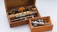 KONVOLUT UHRMACHERWERKZEUG: 1X SCHR.-KOPF- POLIERMASCHINE IM HOLZKASTEN UM 1950, 1X FEDERWINDER FüR ARMBAND- U. TASCHENUHREN (CA. 7-14 ...