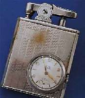 ECLYDO BENZINFEUERZEUG MIT EINGEBAUTER UHR, WOHL DTSCH. 50ER JAHRE, MESSING VERCHR., BER., TANKDICHTHEIT UNGEPR., 16 ST. STIFTEN- ANKERRUNDW., ...