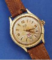 GUB HERRENARMBANDUHR MIT TAG UND DATUM, DEUTSCHLAND 1959, METALL ROTVERG., BER., EDELST.-BODEN GEDR., DATUMSCHNELLKORREKTUR AUßEN 10, AUßER ...