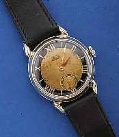 GUB HERRENARMBANDUHR, DEUTSCHLAND UM 1953, METALL NACHVERCHR., EDELST.-BODEN U. GLASR. GEDR., ORIG.-BLATT FL., KAL. 60, 15 ST., HANDAUFZUG, ...