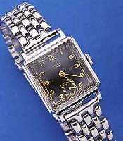 EBEL HERRENARMBANDUHR, SCHWEIZ UM 1945, METALL-CARREE-GEH. HARTVERCHR., EDELST.-BODEN GEDR., KONKAVGL., NEUTR. EDELST.-BAND, ORIG.- BLATT U. ...