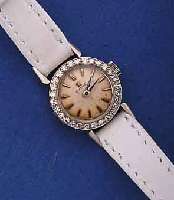 OMEGA DAMENGOLDUHR, SCHWEIZ UM 1961, WG 750/ 000, BODEN GEDR., BRILLANTLÜNETTE, VERS. BLATT, ALTERSBED. ZUM RAND L. FL., FORMANKERW. 17 ST., ...
