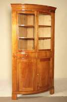 Eckschrank, deutsch, um 1820, Kirschbaum, z .T. massiv, nach vorne gebauchte Front, Oberteil verglast, mittig zwei Schubladen, Schlüsselschilde aus ...