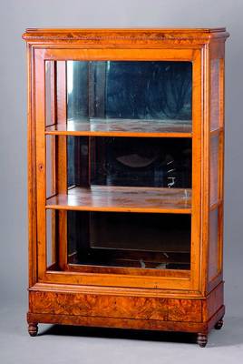 Glasvitrine, westdeutsch, um 1840, Nußbaumfurnier, Rückwand versp., z.T. besch., integr. Fußschublade, abgerundete Ecken, Zierfries, 3 Seiten ...
