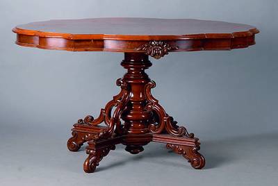 Ovaler Tisch, deutsch, um 1880/90, Mahagoni,4-Kantfuß, reich geschnitzt, in Form v. Akanthusblättern u. Voluten, gedrechselt, Platte geschweift u. ...