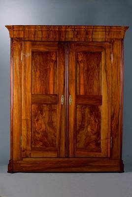 Schrank, um 1820/30, spätes Louis-Seize, Nussbaum massiv, zweitürig, mit acht Kassetten, Kopf getreppt, Fuß passig, l. Gebr.-Sp., M. ca. ...
