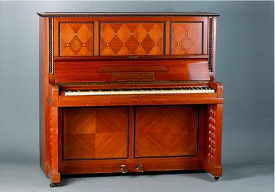 Klavier, deutsch, um 1910, wohl Bruno Paul, Nußbaum/Ahorn, Metallrahmen, seitl. m. freistehenden Säulen, Zierleisten geschwärzt, Kerzenhalter ...