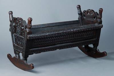 Wiege, 18. Jh., Eiche, unter Verwendung alter Teile, rest., reiche Schnitzereien, Altersschäden, schwundrissig, ca. 60x97x49 cm