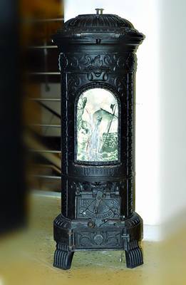 Ofen, Gußeisen, deutsch, um 1900 Runder Ofen mit Emailleplakette, diese stark besch., allseitig verziert, Rocaillendekor, 3 Beine, H. ca. 83 cm