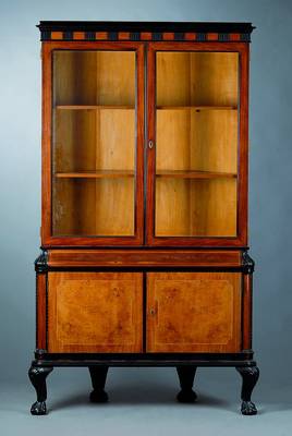 Eckvitrine, wohl Ungarn, um 1925, auf Hart- holz gearbeitet, Palysander, Nussbaum, Wurzel-holzfurnier, Ahorn, Fadenintarsien, Ecken mit ...