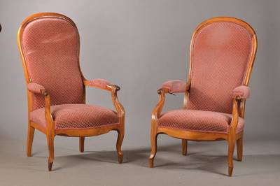 Zwei Voltaire-Sessel, deutsch, um 1860/70, Nussbaum massiv, typisch löffelförmige Rückenlehne, l. geschweifte, dem Körper anschmiegsame Form, ...