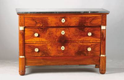 Empire-Kommode, 19.Jh., Nussbaum furniert auf Weichholzkorpus, 3-schübig, Messing-Appliken, seitlich Halbsäulen, schwarze Marmorplatte, ca. ...
