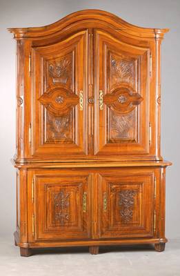 Aufsatzschrank, wohl Freiburg, um 1770/80, Nussbaum massiv, 2-teilig, Unter- und Oberteil je 2-türig, floral aus dem Vollholz geschnitzte Kassetten, ...