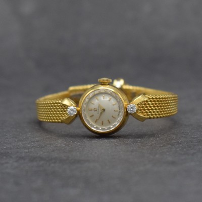 OMEGA Damenarmbanduhr in GG 750/000, Handaufzug, Schweiz um 1960, Ref. 7049, 2- teil. Geh., Boden aufgedr., Band zum Geh. m. 2 Diamanten bes., silb. ...