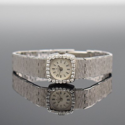 CANDINO Damenarmbanduhr mit Diamantbesatz in WG 750/000, Schweiz um 1970, Handaufzug, Boden aufgedr., Geh. an Goldband 750/000, silb. Zifferbl. m. ...