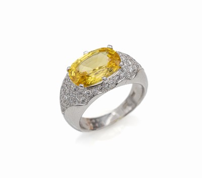 18 kt Gold Saphir-Brillant-Ring, WG 750/000, mittig erhaben gefasster ovalfacett. gelber Saphir ca. 6.49 ct, umgeben von 54 Brillanten zus. ca. 0.96 ...