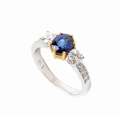 18 kt Gold Saphir Brillant Ring, WG/GG 750/000, mittig in GG gefasster ovalfacett. Saphirca. 1.31 ct, seitl. 2 Brillanten zus. ca. 0.57ct und 6 ...