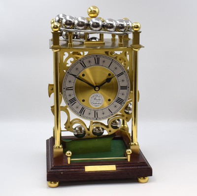 DOVE BAZELAY CHELTENHAM / SINCLAIR HARDING England limitierte Kugellaufuhr, England um 1980, rundes 8-Tage-Messingwerk zwischen 4 Säulen auf ...