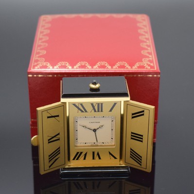 CARTIER kleiner Tischwecker, Schweiz um 1980, quarz, verg. Geh. m. Sonnendekor teils schwarz lackiert, Schmuckkrone, aufklappbar, röm. Zahlen, ...