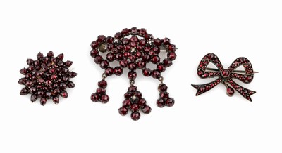 Konvolut 3 Granat-Broschen, Tombak, Böhmen um 1890, 1 x geschwungen mit 3 bewegl. Abhängungen, ca. 4.2 x 5 cm, 1 x schleifenf., ca. 3 x 2 cm, und ...