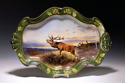 Große ovale Platte, Nymphenburg, um 1900, reich bunt handbemalt mit röhrendem Hirsch in Landschaft, Rand mit goldenem Eichenlaub auf grünem Grund, ...