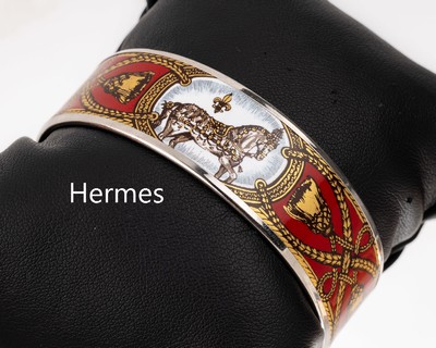HERMES Email Armreif, Metall, rotgrundig emaill., umlaufendes Motiv mit Pferden, goldfarbene Quasten und Bändern, sign. Hermes Paris, D. ca. 6.2 cm