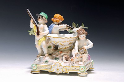 Seltener Tafelaufsatz mit Putten, Meissen, um 1900, zentrale Muschelschale auf Felsen, umgeben von drei Putten mit jagdlichen Attributen: zwei mit ...