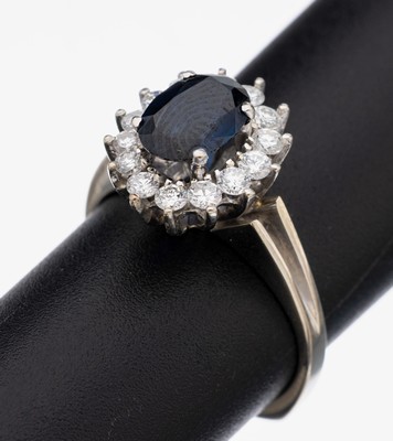18 kt Gold Saphir-Brillant-Ring, WG 750/000, mittig ovalfacett. Saphir ca. 1.25 ct, umgeben von 14 Brillanten zus. ca. 0.43 ctWeiß/si, RW 54, ca. ...