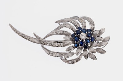 18 kt Gold Saphir Brillant Brosche, WG 750/000, Blütenform, teilmatt. und struk- turiert, 12 rundfacett. Saphire zus. ca. 1.0 ct, 1 Brillant ca. ...