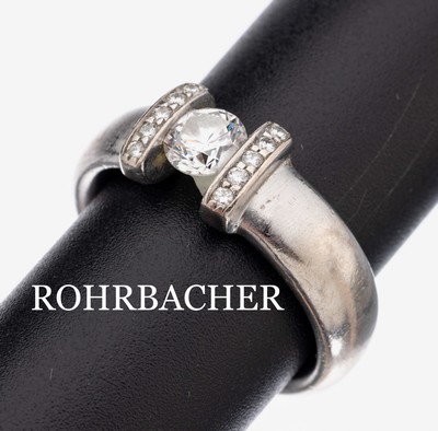 18 kt Gold Brillant-Ring, WG 750/000, Brillant ca. 0.60 ct feines Weiß/si, 10 Brillanten zus. ca. 0.105 ct feines Weiß/lp, RW 55, ca. 13 g, mit ...