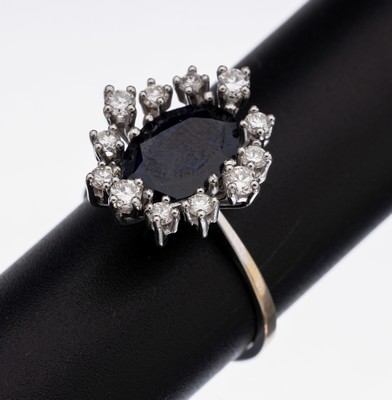 18 kt Gold Saphir-Brillant-Ring, WG 750/000, Ringkopf in mehreren Ebenen, mittig ovalfacett. Saphir ca. 2.0 ct, umgeben von 12 Brillanten zus. ca. ...