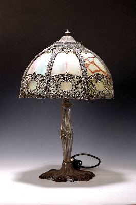 Tischlampe, wohl USA, um 1910/20, Eisenfuß floral verziert, Schirm aus Metall mit leicht farbigen Opakglaseinsätzen, in Durchbruch verziert, zwei ...