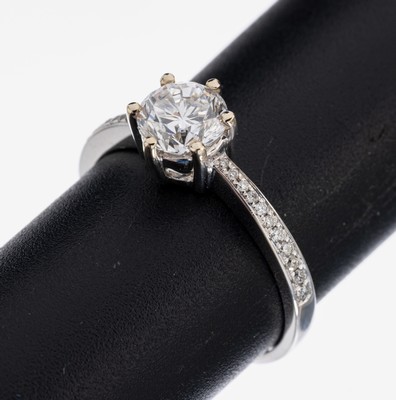 18 kt Gold Brillant-Ring, WG 750/000, mittig Brillant ca. 1.00 ct hochfeines Weiß(E)/vvs2, Ringschultern mit Brillanten zus. ca. 0.12 ct feines ...