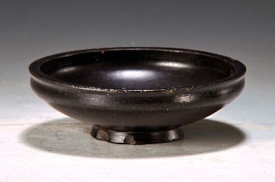 Etruskische Bucchero Schale, 5./6.Jh., schwarz gebrannte Keramik, mehrfach bestoßen, alte Durchbohrung, auf rundem Stand, D. 19 cm, Provenienz: ...
