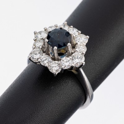 14 kt Gold Saphir-Brillant-Ring, WG 585/000, mittig erhaben gefasster rundfacett. Saphir ca. 1.0 ct, umgeben von 12 Brillanten zus. ca. 1.20 ct ...