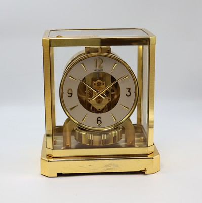 LeCoultre Tischuhr Serie Atmos Referenz 5090, Schweiz um 1960, verg. Geh. 5-seitig verglast, silb. Ring-Zifferbl. m. gold. Ind., Dauphinezeiger, ...