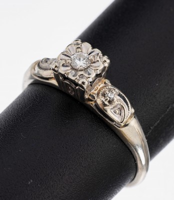 14 kt Gold Diamant-Ring, WG 585/000, mittig erhaben gefasster Brillant ca. 0.05 ct Weiß/si, Ringschultern mit 2 8/8-Diamanten zus. ca. 0.02 ct ...