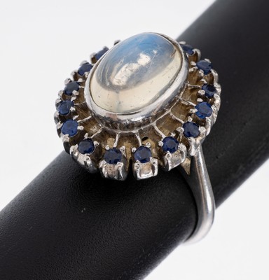 14 kt Gold Mondstein-Saphir-Ring, WG 585/000, mittig erhaben gefasster ovaler Mondstein-Cabochon ca. 5.0 ct, 16 rundfacett. Saphire zus. ca. 0.32 ...