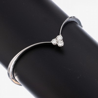 18 kt Gold Brillant-Armreif, WG 750/000, geschwungene Grundform, 3 im Dreieck angeordnete Brillanten zus. ca. 0.60 ct feinesWeiß-Weiß/vs, D. ca. ...