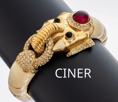 Armreif CINER, USA 1950er Jahre, "Elefantenkopf", Metall vergoldet, cremefarbener Hartlack, roter, grüner und farbloser Strassbesatz, ca. ...