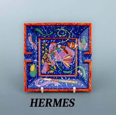 HERMES Aschenbecher, weißes Porzellan, blauer Grund mit orangefarb. Rand, Darstellungeines Paradiesvogels, Boden mit Velourleder, ca. 16 x 16 cm
