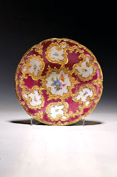 Prunkteller, Meissen, 20. Jh., 1. Wahl, partiell dunkelrot glasiert, reich reliefiert und matt- und glanzvergoldet, bunte Blumen, D. ca. 28cm
